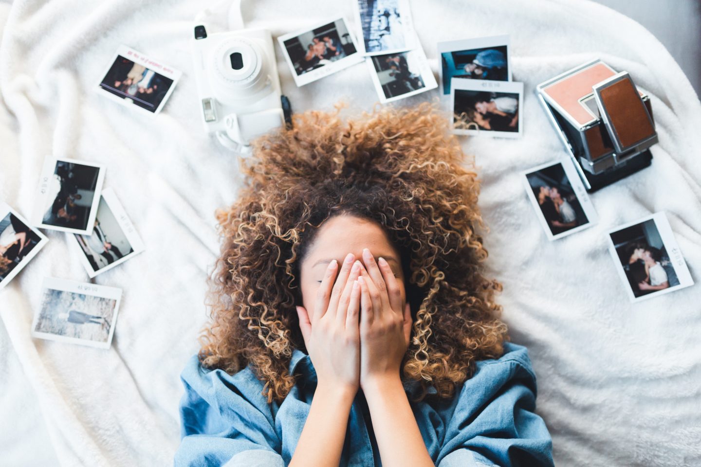woman laying on bed surrounded my photos for social media