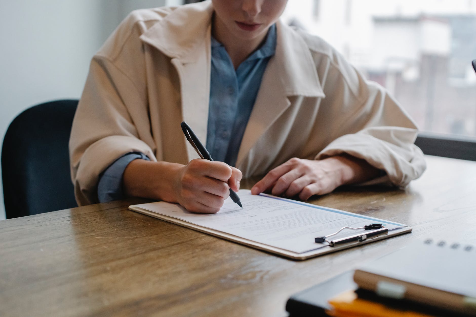 focused woman writing in clipboard while hiring candidate